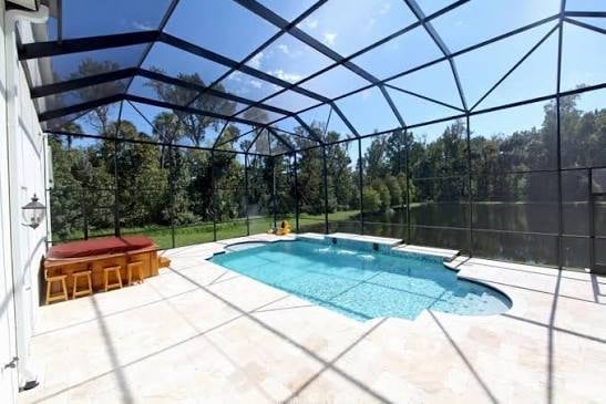 Screened-in residential swimming pool surrounded by lounge chairs with tropical landscaping visible in the background